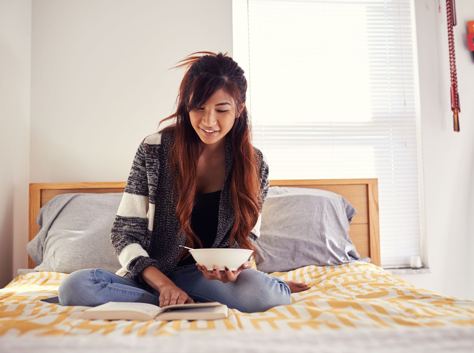 A young lady relaxing on a bed and focused on a book, illustrating the joy of being caught reading during Get Caught Reading Month.
