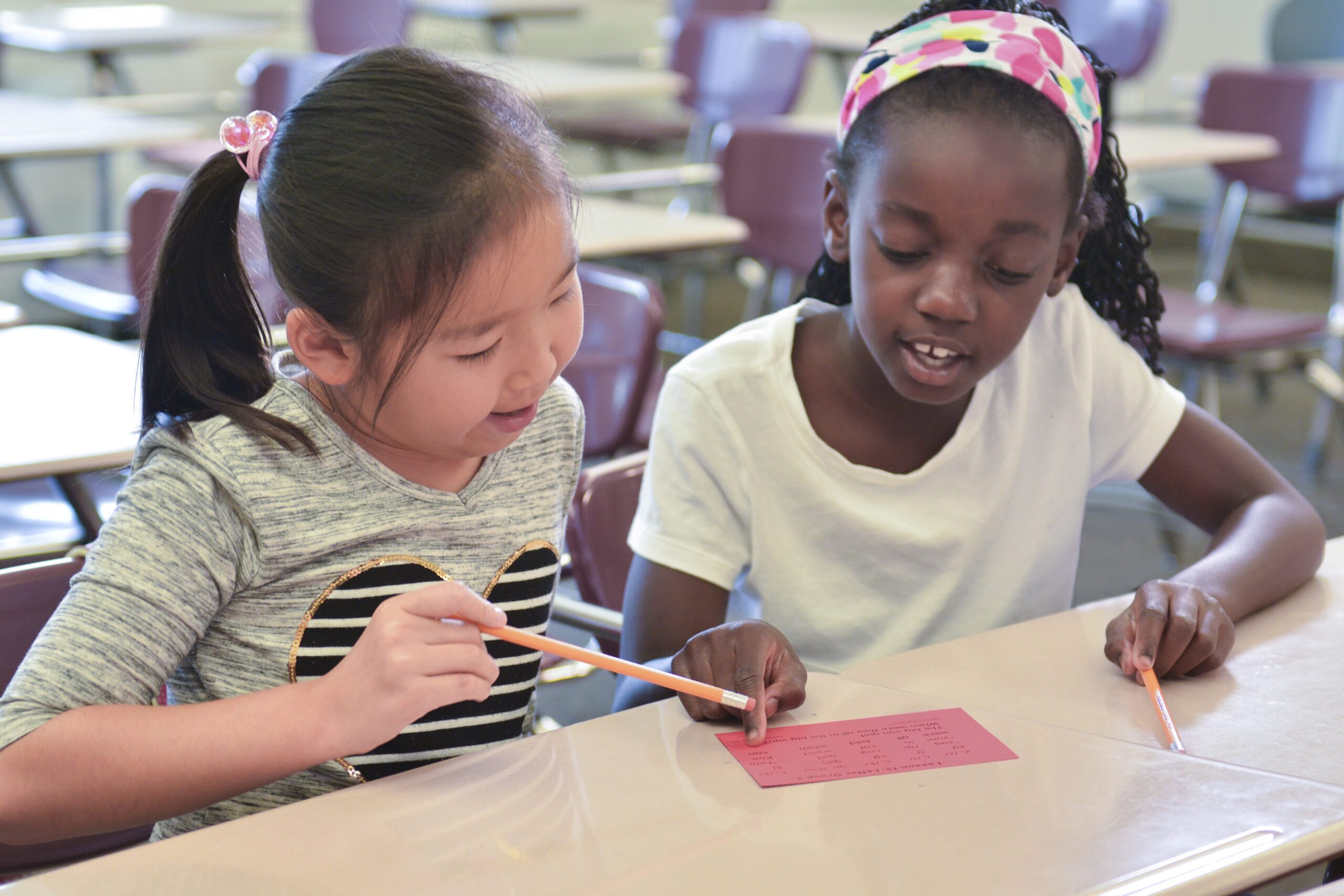 Two diverse elementary students working together on a colorful art project in a culturally competent classroom setting.