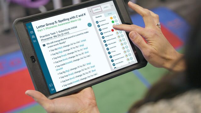 A teacher using an iPad to access the Reading Horizons Discovery data dashboard to track student mastery and cued-up lessons.