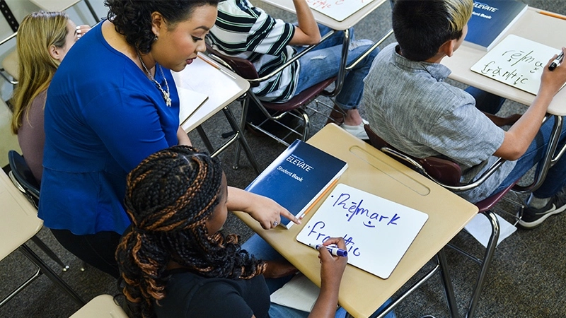 A teacher helps a teenage student as she is decoding the word "frantic."