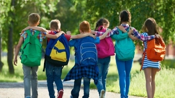 Kids walking to arm-in-arm with backbacks
