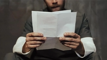 An inmate sits on his bed reading a letter.