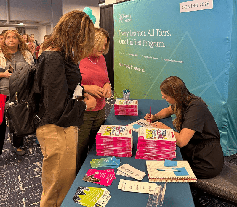 Lindsay Kemeny signing a book at the Reading Horizons booth at The Reading League 2025 conference