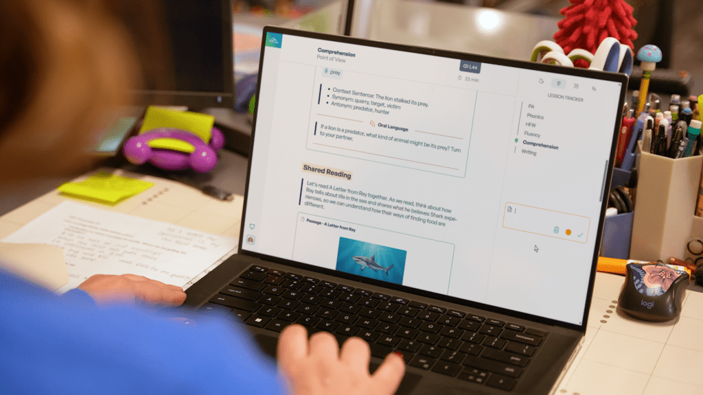 Teacher uses a comprehension lesson tracker with a shared reading passage on a laptop.