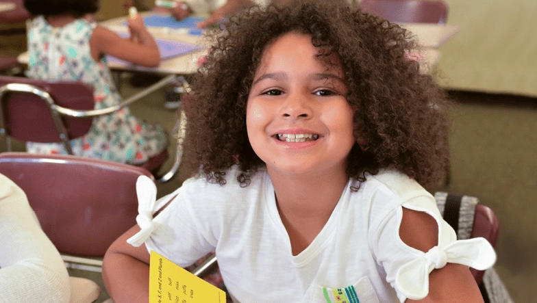 young girl holding transfer cards and smiling