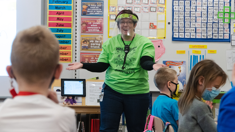 teacher in classroom wearing a face shield while teaching during COVID