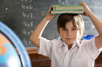 boy holding books with globe in front and chalkboard behind