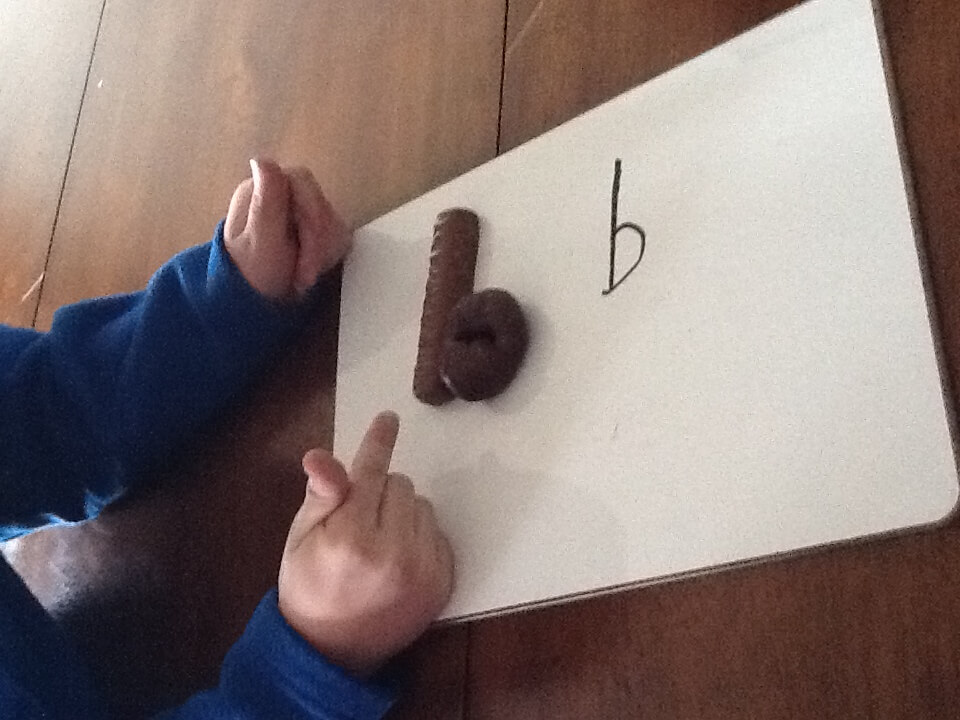 Student writing the letter b on a whiteboard