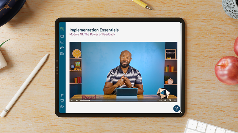 An iPad laying on a desk, displaying an Implementation Essentials coaching video in the Reading Horizons Discovery Software.