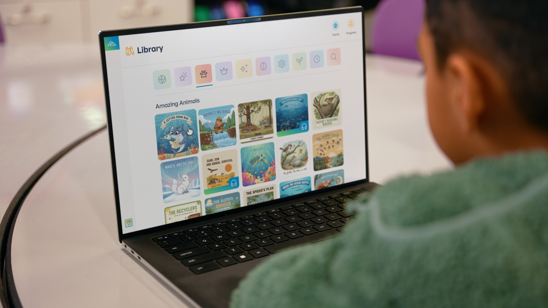 Student browses a digital library of animal-themed reading titles on a laptop.