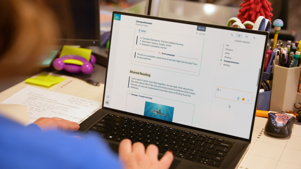 Teacher uses a comprehension lesson tracker with a shared reading passage on a laptop.